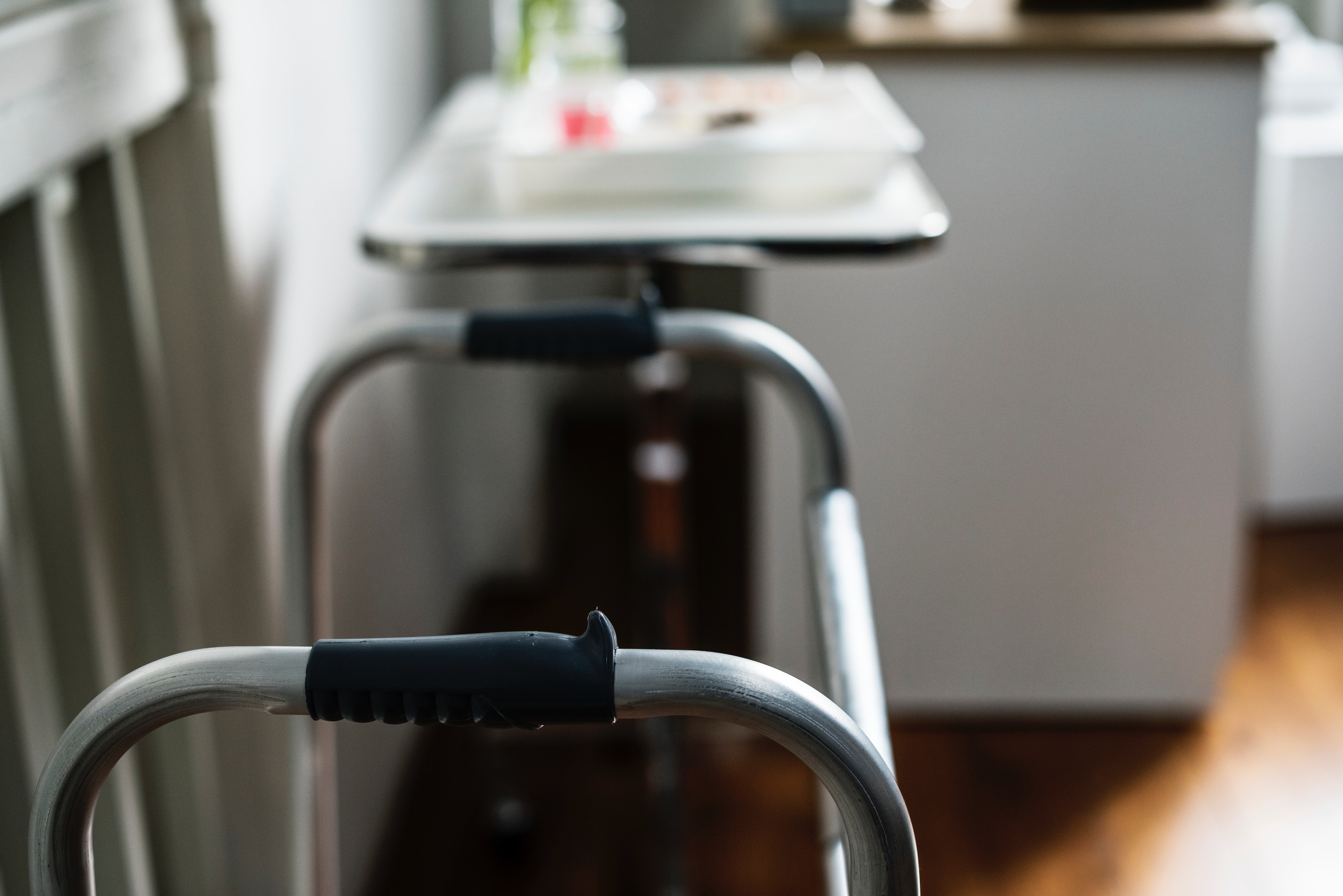 walker handles with black grips, bedside table with medications